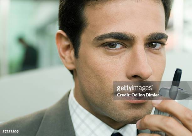 businessman holding cell phone near face - three quarter length stock pictures, royalty-free photos & images