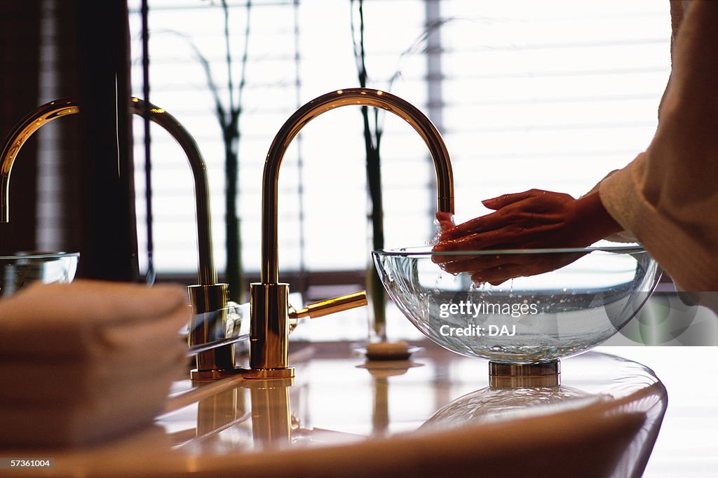 Person at bathroom basin, water running through fingers, Jin Mao tower (Grand Hyatt)