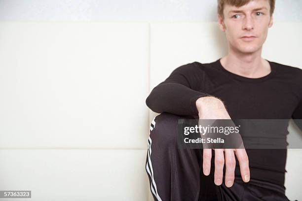 man sitting on sofa and looking away - hand on knee stock pictures, royalty-free photos & images