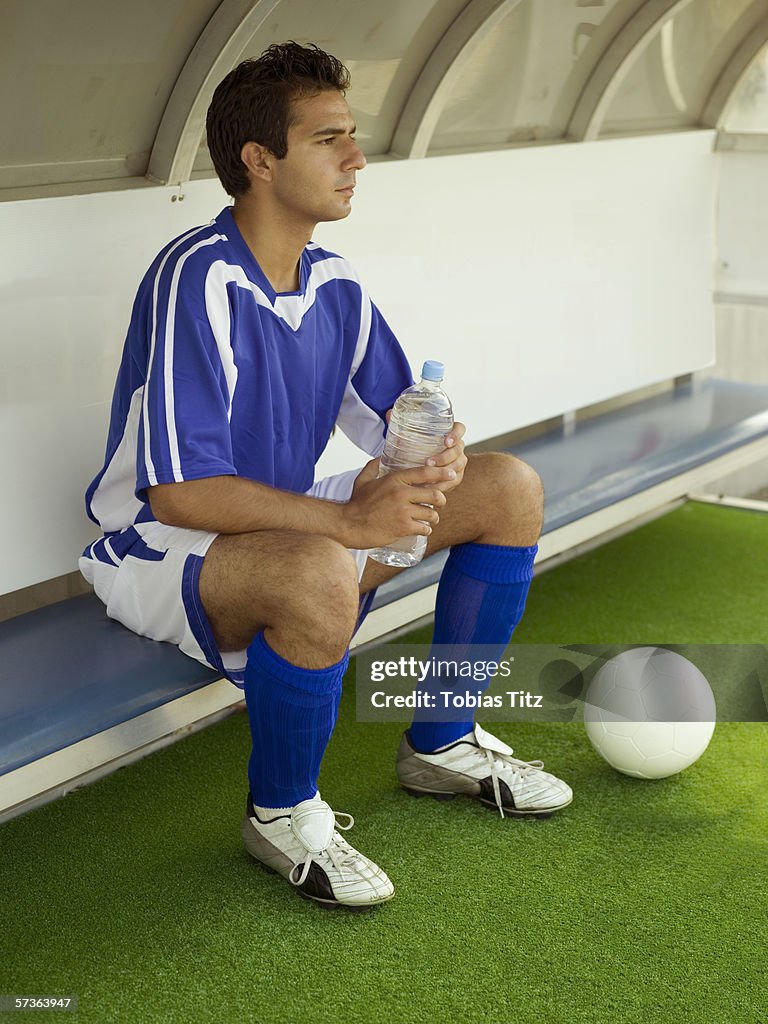 A soccer player sitting on the bench