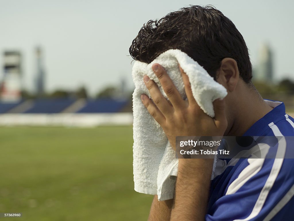 A soccer player wiping his face with a towel