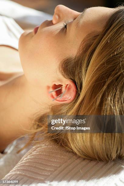 close-up of woman with acupuncture needles on ear - ear close up women stock-fotos und bilder