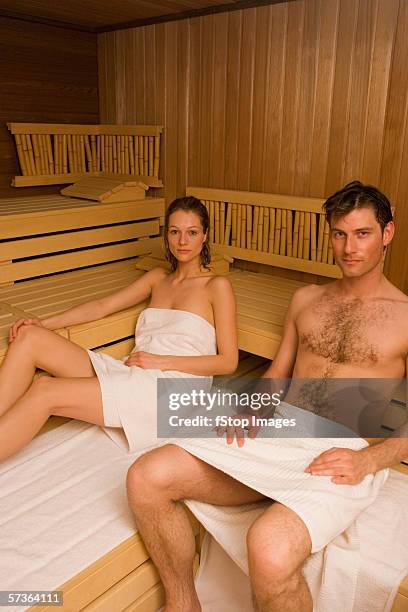 couple wrapped in towels and sitting in sauna - female hairy chest stock-fotos und bilder