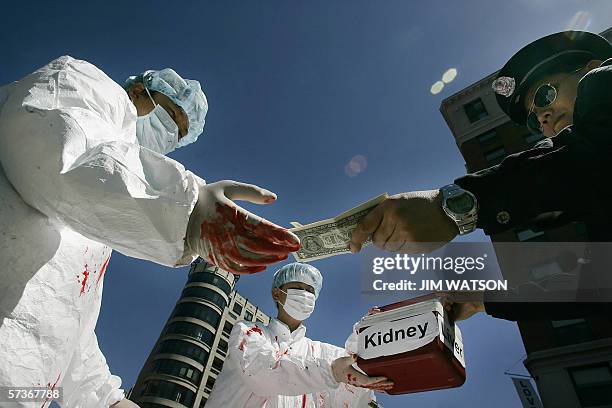 Washington, UNITED STATES: Falun Gong demonstartors dramatize an illegal act of paying for human organs during a protest 19 April 2006 in Washington,...