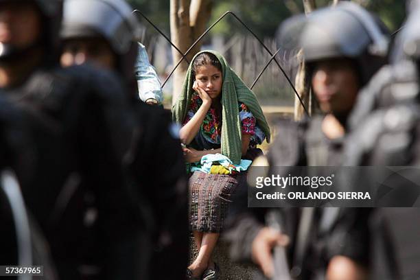 Una joven indigena observa agentes antimotines y de reaccion inmediata de la Policia Nacional Civil que realizan ejercicios en la Plaza de la...