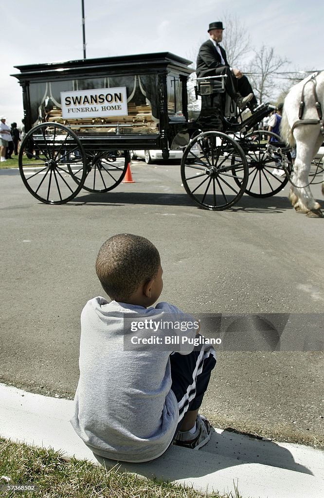 Huddy Rapper Funeral A young boy sits on a curb and watches the horse-drawn hearse that ...
