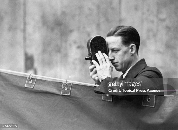 Jack Purcell, the Canadian champion, uses his cine-camera to record the play at the All England Badminton Championships in the Royal Horticultural...