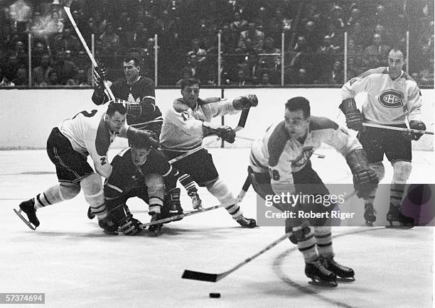 Canadian professional hockey players and Montreal Canadiens teammates Doug Harvey and Dickie Moore attempt to block an opposing player from the...