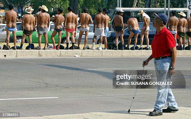 Man passes by naked peasants, members of the indigenous group "400 Pueblos" during a protest at Mexico City's Reforma Avenue 20 April 2006. The group...