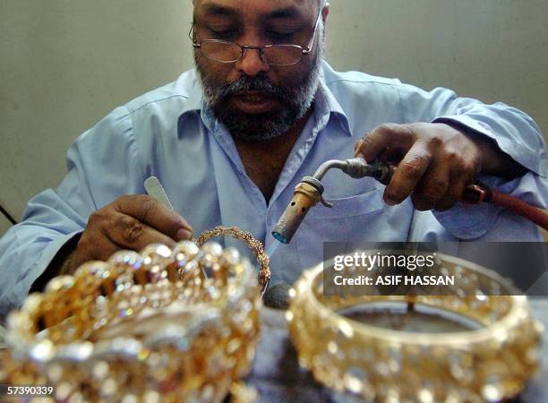 Pakistani jewellery worker prepares an anklet at a gold shop in Karachi, 21 April 2006. The rising trend in the prices of gold in the country is...