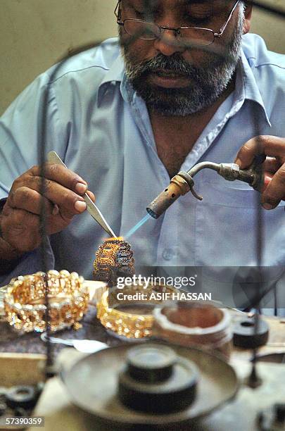 Pakistani jewellery worker prepares an anklet at a gold shop in Karachi, 21 April 2006. The rising trend in the prices of gold in the country is...