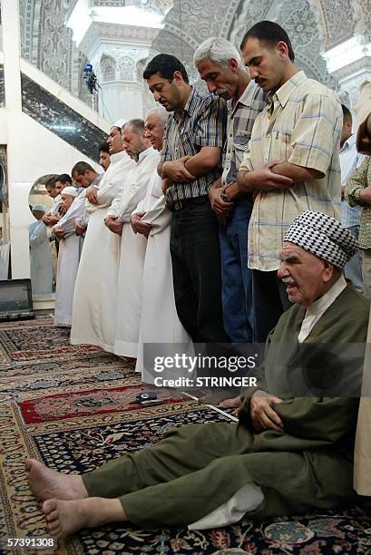 Crippled Iraqi Sunni man prays on the floor beside other men stading for weekly Friday noon prayer at the Abu Hanifa mosque in Baghdad, 21 April...