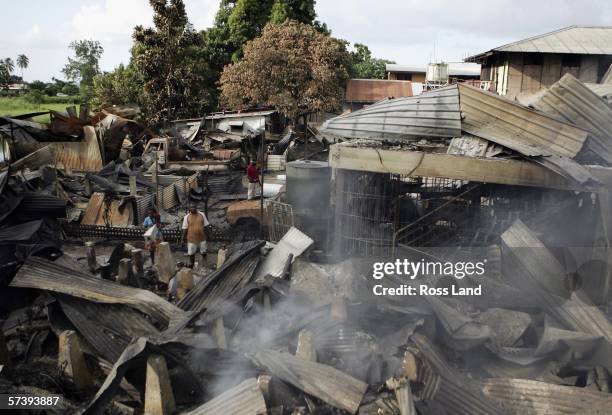 Locals search through the remains of smouldering buildings in China Town on April 21, 2006 following several days of rioting and looting in the...