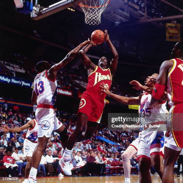 Dominique Wilkins of the Atlanta Hawks shoots a jump shot against Clarence Weatherspoon of the Philadelphia 76ers during a game at The Spectrum on...