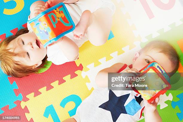 boy and girl toddler on colorful mat playing toys - 敷物 マット ストックフォトと画像