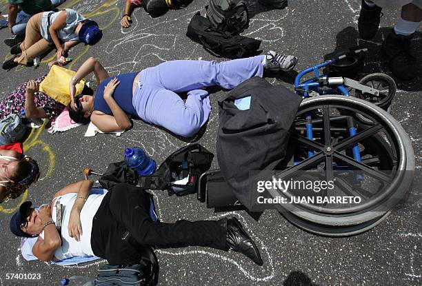 Protesters lie down on the tarmac mocking to be dead during a massive rally 22 April, 2006 in Caracas. Thousands of Venezuelans marched Saturday...