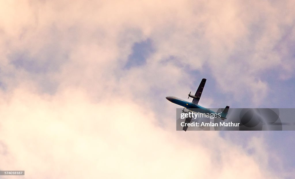 Propellor plane flying in pink clouds