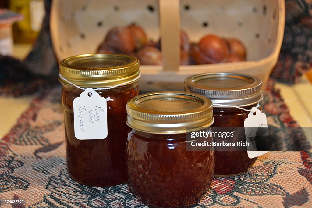 Canned plum jelly with basket and plums in back