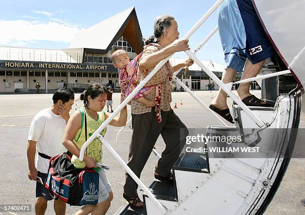 Mother and child, some of the nearly 300 Chinese who fear for their safety, board their flight as they are flown out of the troubled Solomon Islands...