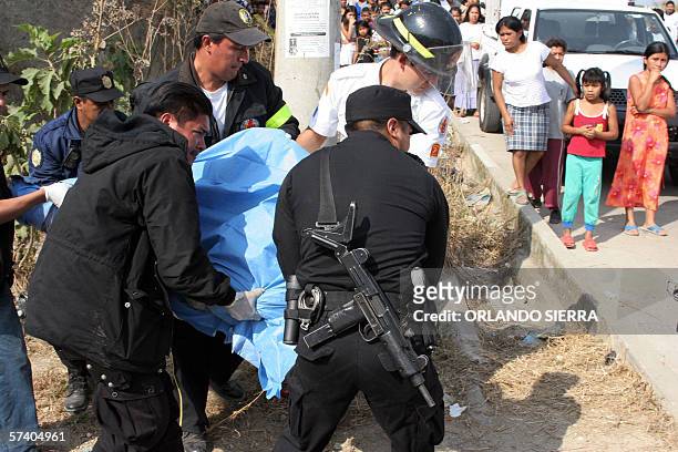 Agentes de la Policia Nacional Civil y miembros del Cuerpo de Bomberos Voluntarios cargan el cadaver de una mujer, asesinada junto a su hija en la...