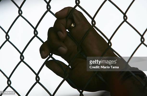 An inmate holds onto a fence during the Angola Prison Rodeo at the Louisiana State Penitentiary April 23, 2006 in Angola, Louisiana. The Angola...