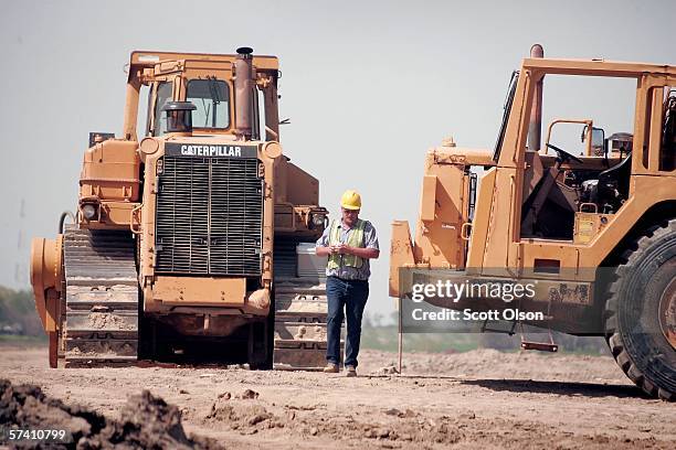 Heavy equipment operator walks between Caterpillar earth moving equipment at a road construction site on April 24, 2006 near Joliet, Illinois. Heavy...