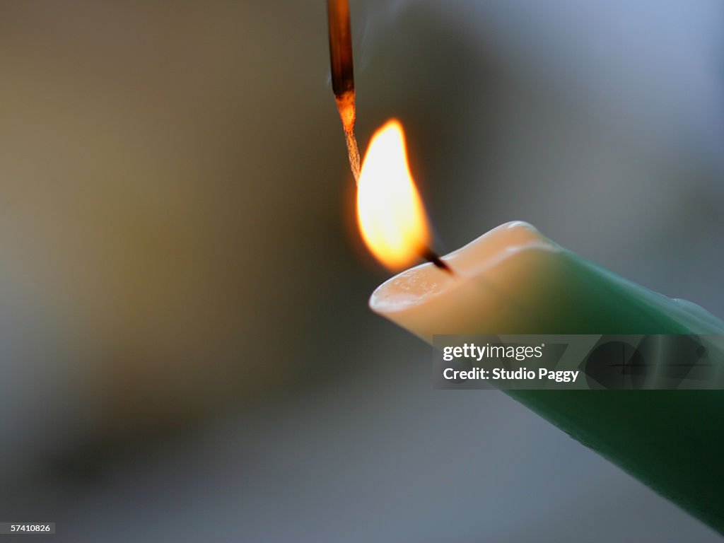 Close-up of a burning candle and an incense stick