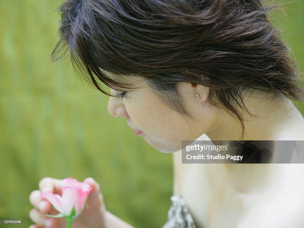 Side profile of a young woman looking at a flower