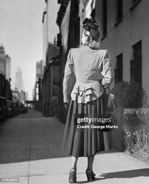 elegante mujer de pie solo en la acera, vista trasera (b & p - 1940s fotografías e imágenes de stock