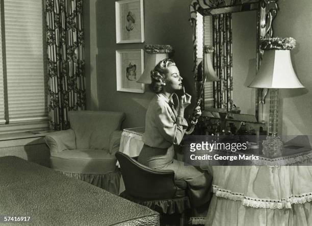 woman applying lipstick at vanity table, (b&w) - 1940s bedroom stock pictures, royalty-free photos & images