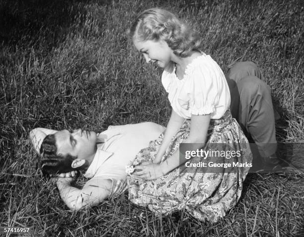 young couple resting on lawn, (b&w) - retro couple stock pictures, royalty-free photos & images