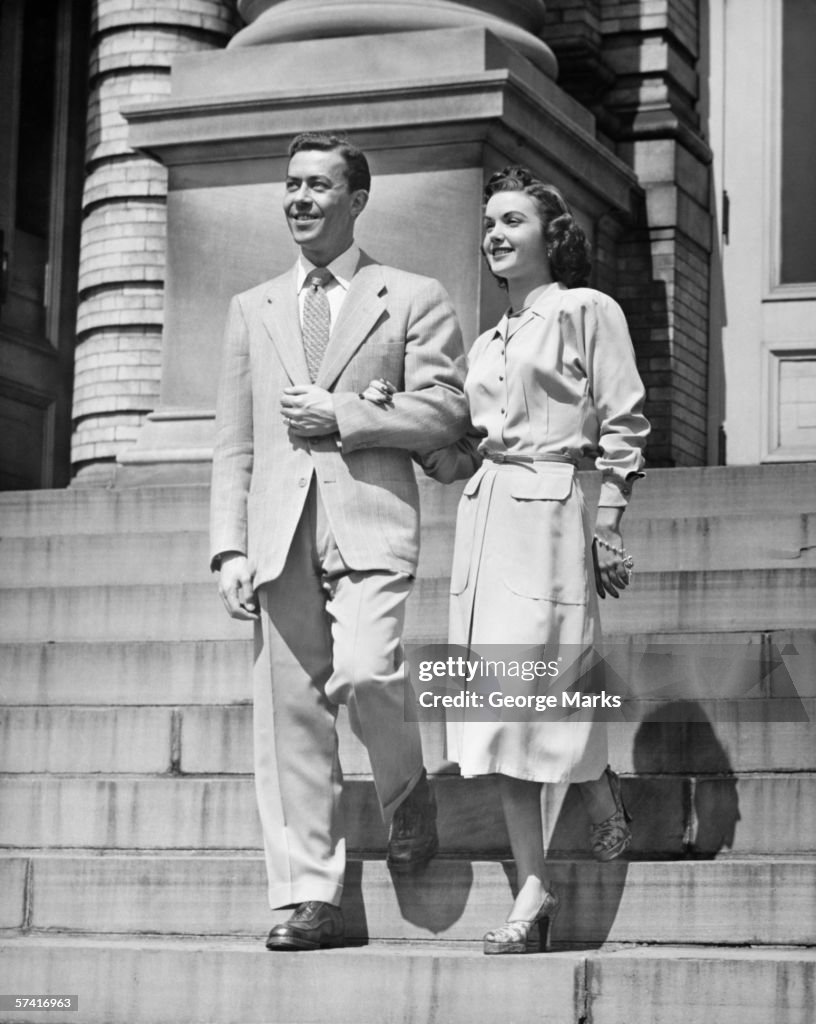 Elegant couple descending steps, (B&W)