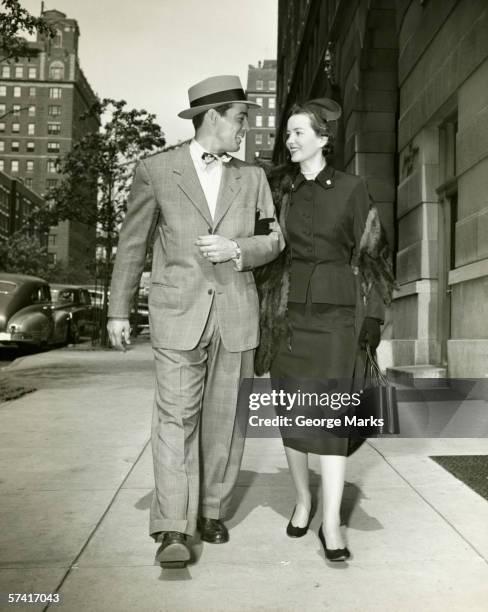 elegant couple walking on sidewalk, (b&w) - 1950s couple stock pictures, royalty-free photos & images