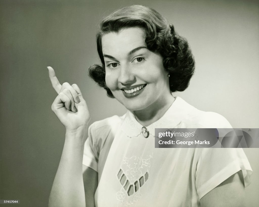 Smiling woman pointing finger in studio, (B&W), (Close-up), (Portrait)