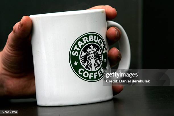 Man holds Starbucks Coffee mug in central London on April 25, 2006 in London, England. The all traditional English style Breakfast 'Fry-Up' is under...