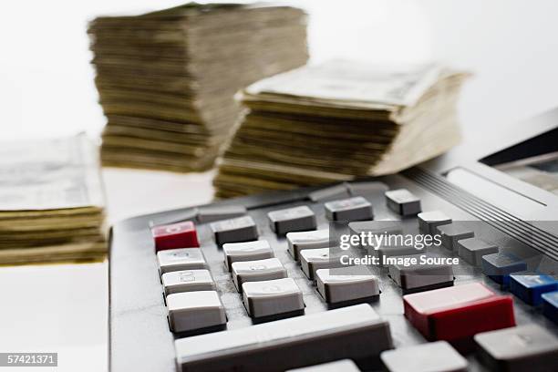 calculator and stacks of banknotes - blanqueo de dinero fotografías e imágenes de stock