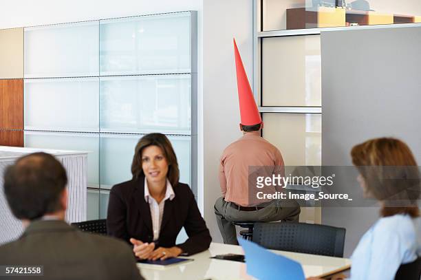 businessman sat in corner with dunce cap - dunce cap stock pictures, royalty-free photos & images