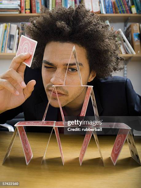 close-up of a young man making a house of cards - house of cards stock pictures, royalty-free photos & images