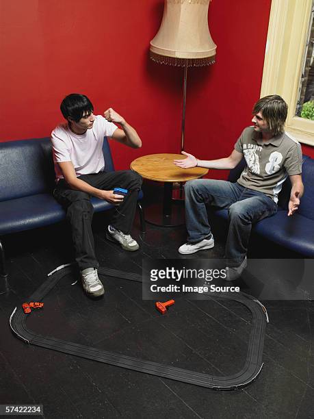 zwei freunde spielen mit einem spielzeug race track - auto sofa stock-fotos und bilder