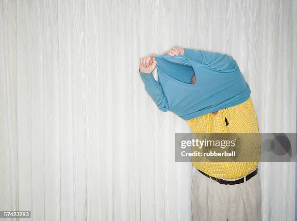 senior man taking off his sweater - spogliarsi foto e immagini stock