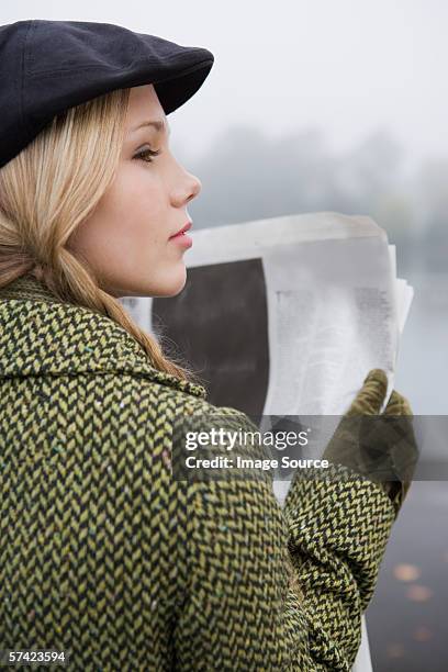 young woman reading newspaper - flat cap stock pictures, royalty-free photos & images