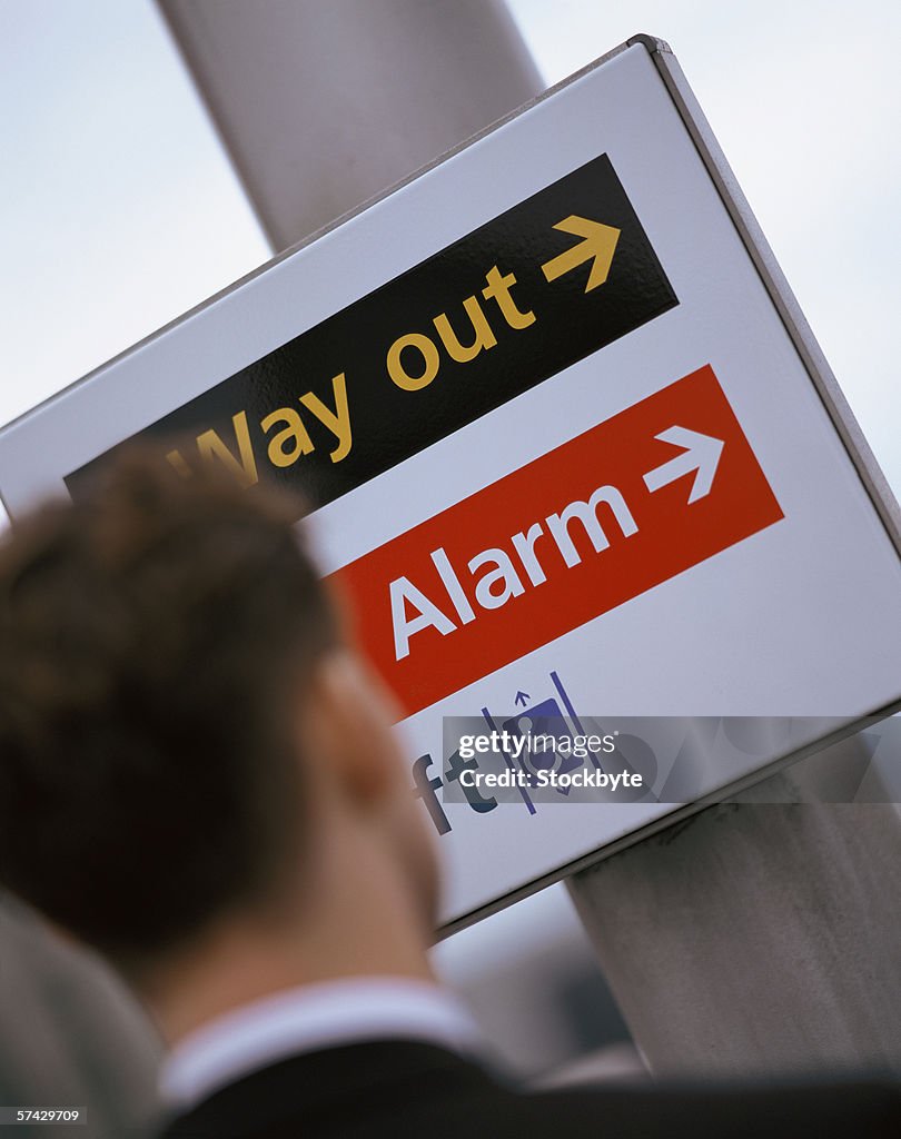 Rear view of a businessman standing in front of a sign post