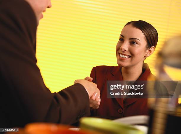 young business executives shaking hands - business woman in red suit jacket stock pictures, royalty-free photos & images