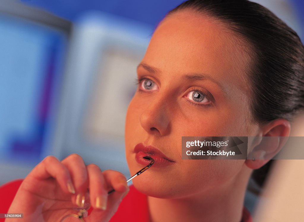 Close-up of a young woman touching the shaft of her eye glasses to her lip (toned)