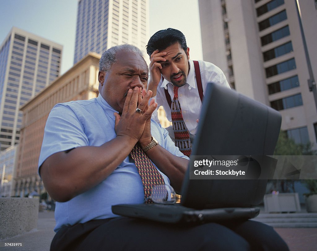 Close-up of two businessmen shocked at the data on a laptop screen