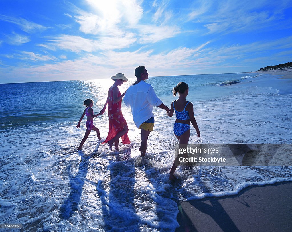 A family holding hands and walking together on a beach