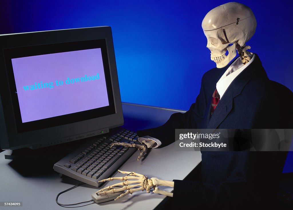 View of a skeleton sitting in front of a computer