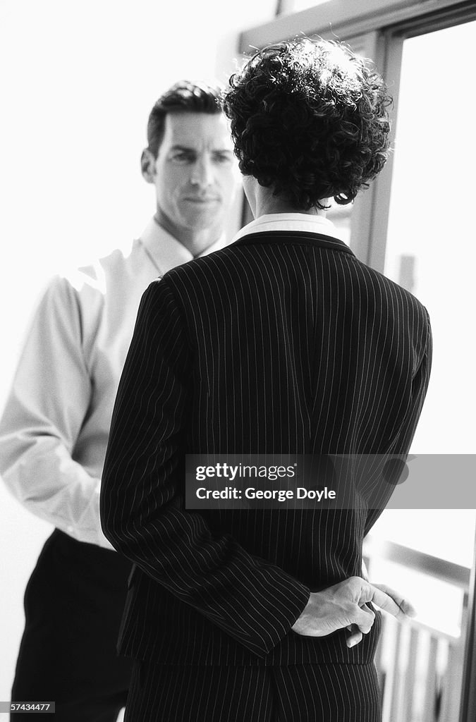 Black and white view from behind of a woman shaking a man's hand