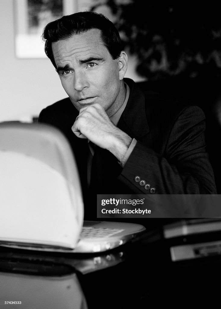 Black and white portrait of a businessman thinking at his desk