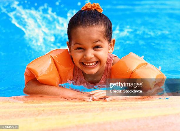 portrait of a young girl (3-5) wearing arm floats in a swimming pool - arm floats stock-fotos und bilder